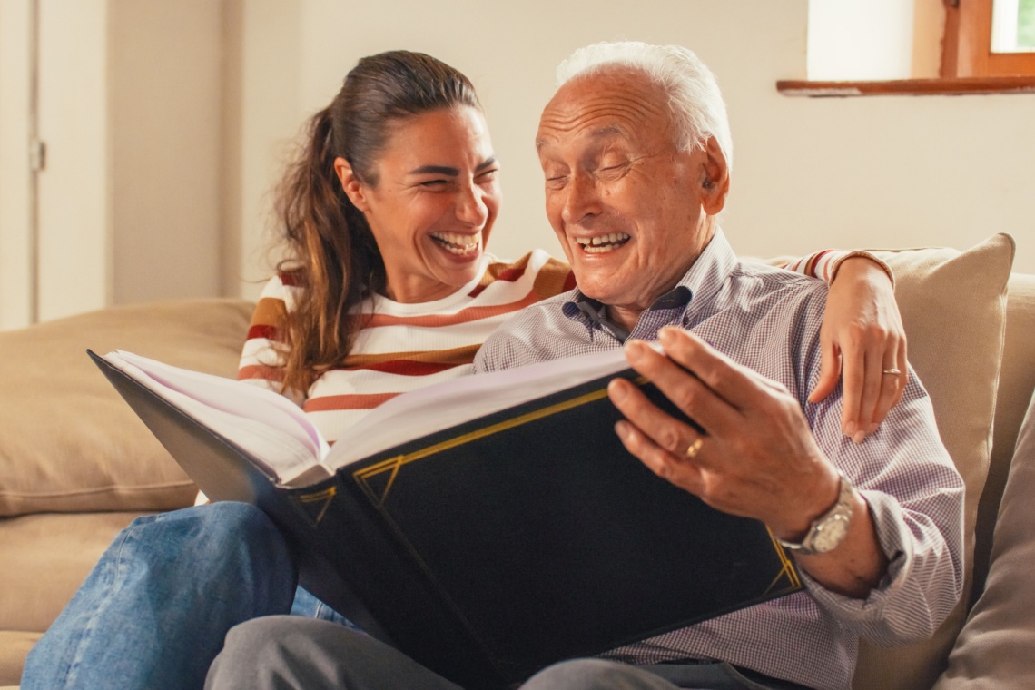 Old father and younger daughter looking at a photo album and sharing memories